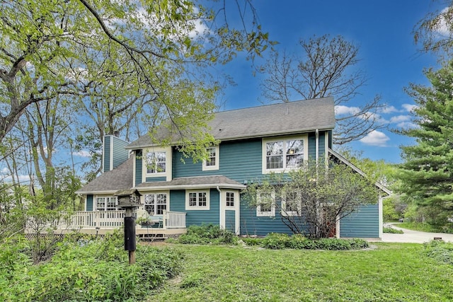 view of front of home with a chimney, a wooden deck, and a front lawn