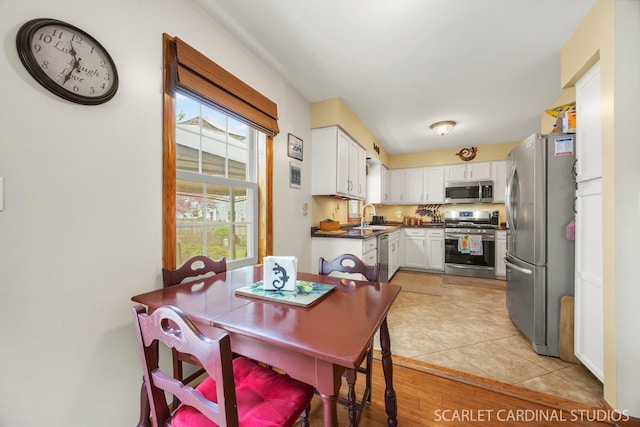 485 Mayfield Ln, Aurora, IL 60504 - kitchen with stainless steel appliances, white cabinetry, dark countertops, a sink, and light tile patterned flooring