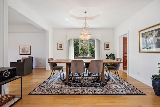 dining area with wood finished floors, a chandelier, and baseboards
