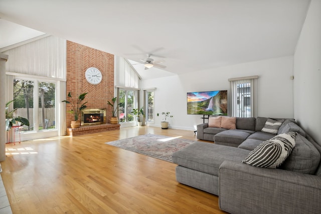 living room with ceiling fan, healthy amount of natural light, wood finished floors, a fireplace, and high vaulted ceiling
