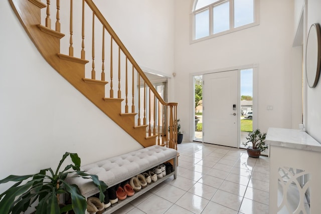 foyer featuring a high ceiling, plenty of natural light, stairs, and light tile patterned floors