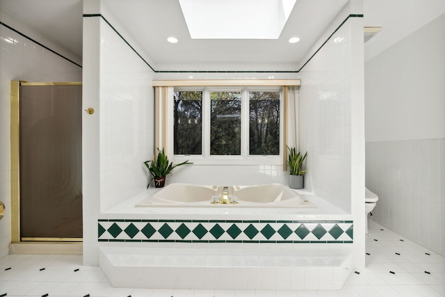 full bath featuring tile patterned flooring, a garden tub, a shower stall, toilet, and tile walls
