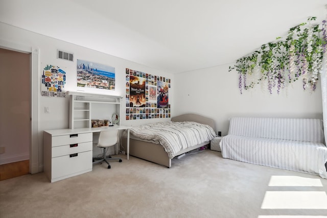 bedroom with light colored carpet and an office area