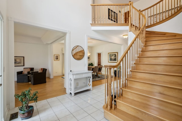 entryway with stairs, tile patterned flooring, and a towering ceiling