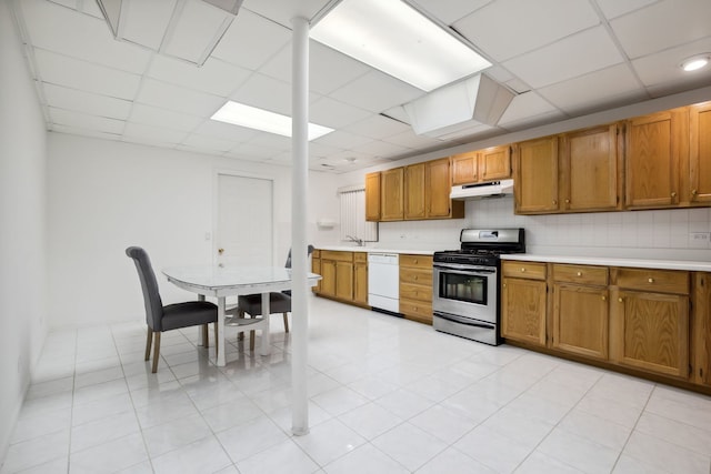 kitchen with stainless steel gas stove, dishwasher, under cabinet range hood, light countertops, and brown cabinetry