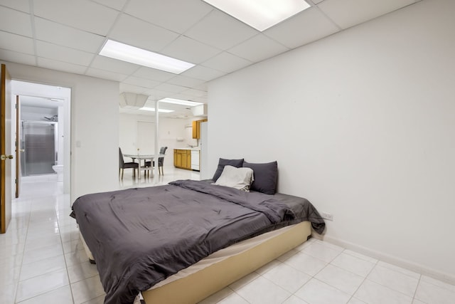 bedroom with light tile patterned flooring, a drop ceiling, and connected bathroom
