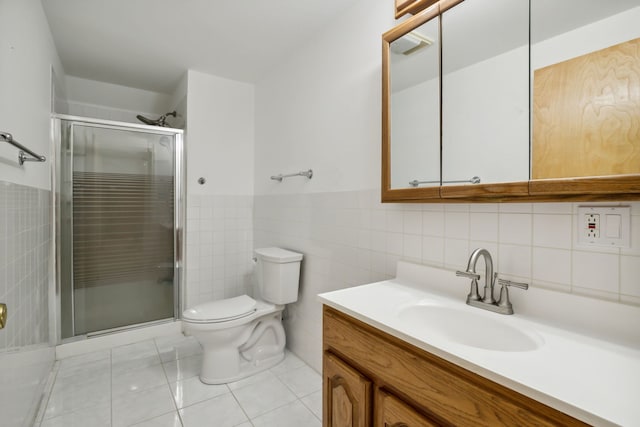 bathroom with a stall shower, toilet, tile walls, vanity, and tile patterned floors