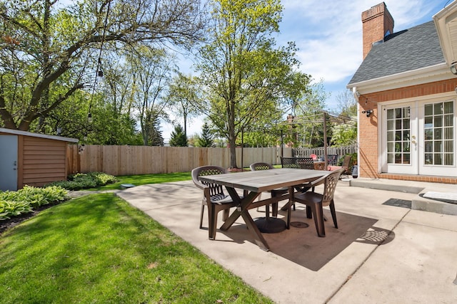 view of patio with french doors, outdoor dining area, an outbuilding, and a storage shed