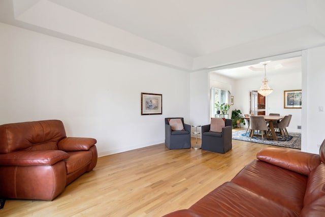 living area featuring light wood-type flooring, a chandelier, and baseboards