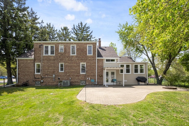 rear view of property with french doors, a patio, central AC unit, a chimney, and a lawn