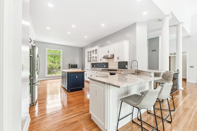 3302 Greenwood Ln, Saint Charles, IL 60175 - kitchen featuring blue cabinets, a breakfast bar, recessed lighting, under cabinet range hood, and light wood-style flooring