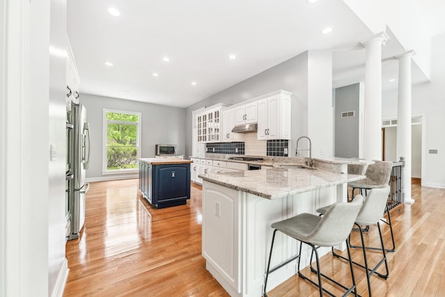 3302 Greenwood Ln, Saint Charles, IL 60175 - kitchen featuring a sink, blue cabinets, under cabinet range hood, a breakfast bar, and light wood-style floors