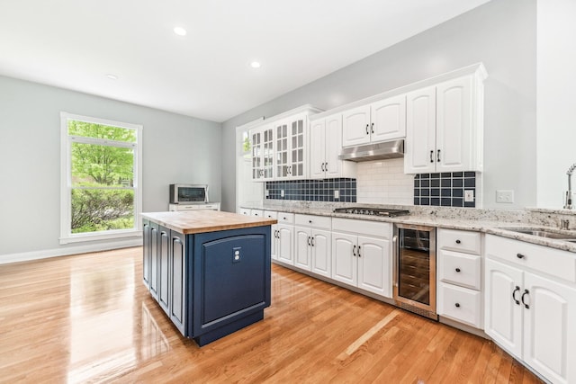 3302 Greenwood Ln, Saint Charles, IL 60175 - kitchen with beverage cooler, wooden counters, under cabinet range hood, stainless steel gas cooktop, and white cabinets