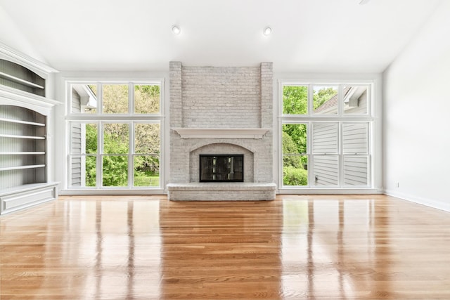 3302 Greenwood Ln, Saint Charles, IL 60175 - unfurnished living room featuring wood finished floors, healthy amount of natural light, a brick fireplace, lofted ceiling, and built in shelves