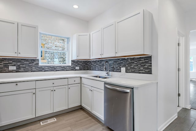 7709 S Eberhart Ave, Chicago, IL 60619 - kitchen with stainless steel dishwasher, a sink, backsplash, light wood finished floors, and white cabinets