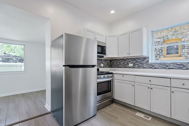 7709 S Eberhart Ave, Chicago, IL 60619 - kitchen featuring appliances with stainless steel finishes, light countertops, backsplash, light wood-type flooring, and white cabinets