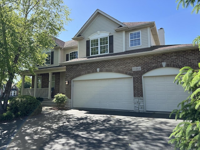 13464 Skyline Dr, Plainfield, IL 60585 - view of front of property featuring brick siding, a chimney, a garage, a porch, and driveway