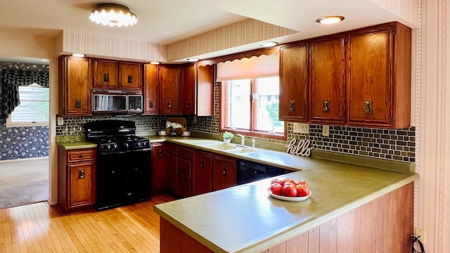 1305 Baugh Dr, Normal, IL 61761 - kitchen featuring black appliances, wallpapered walls, a sink, light wood-type flooring, and a peninsula