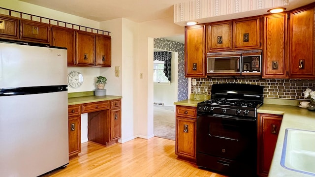 1305 Baugh Dr, Normal, IL 61761 - kitchen featuring freestanding refrigerator, black range with gas stovetop, light wood-type flooring, light countertops, and tasteful backsplash
