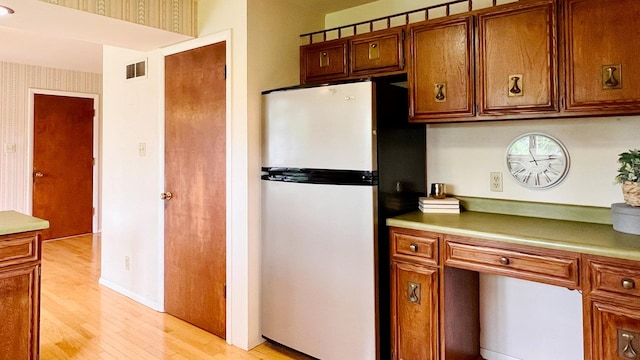 1305 Baugh Dr, Normal, IL 61761 - kitchen featuring freestanding refrigerator, light wood-style floors, brown cabinetry, light countertops, and built in study area