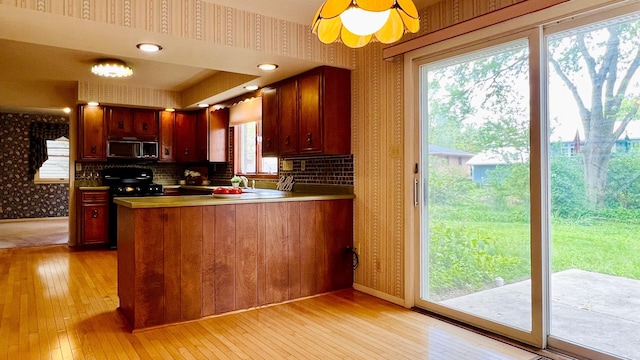1305 Baugh Dr, Normal, IL 61761 - kitchen with wallpapered walls, stainless steel microwave, light wood-type flooring, black gas range oven, and a peninsula