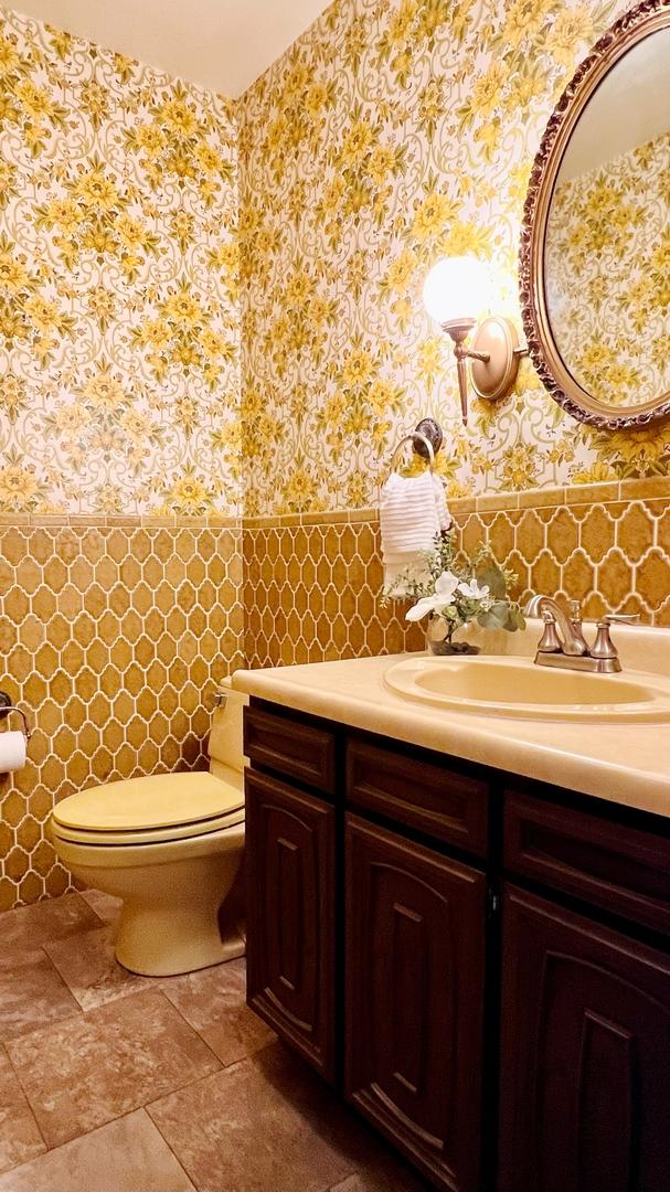 1305 Baugh Dr, Normal, IL 61761 - bathroom featuring wallpapered walls, a wainscoted wall, toilet, vanity, and tile walls