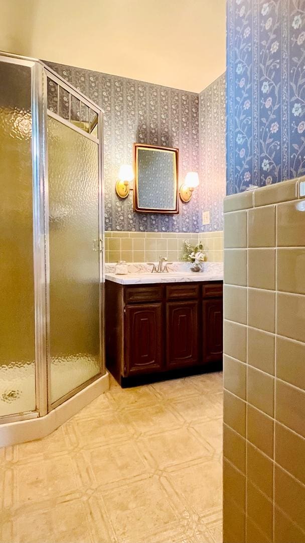 1305 Baugh Dr, Normal, IL 61761 - bathroom with wallpapered walls, vanity, a shower stall, tile walls, and wainscoting