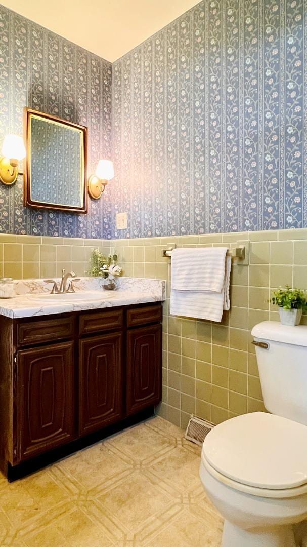 1305 Baugh Dr, Normal, IL 61761 - bathroom with tile walls, toilet, wallpapered walls, wainscoting, and vanity