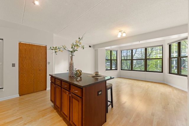 kitchen featuring light wood-style flooring, a center island, healthy amount of natural light, a kitchen bar, and a textured ceiling