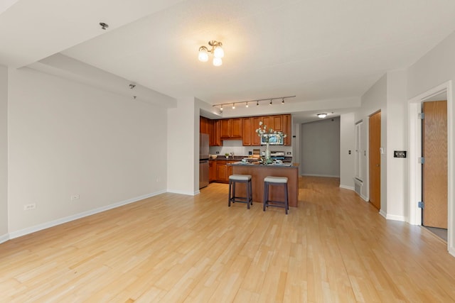 kitchen featuring dark countertops, appliances with stainless steel finishes, open floor plan, and light wood finished floors