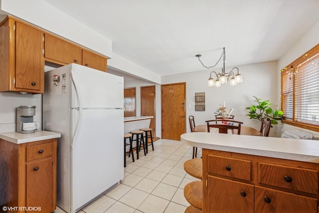 6810 N Ozark Ave Unit 9, Chicago, IL 60631 - kitchen featuring freestanding refrigerator, light tile patterned flooring, light countertops, and a chandelier