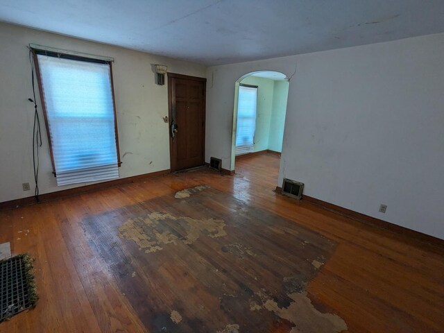7317 S Mozart St, Chicago, IL 60629 - unfurnished living room with arched walkways, wood finished floors, and baseboards