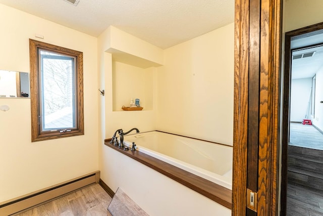 1479 Old Mill Rd, Franklin Grove, IL 61031 - full bath with a baseboard heating unit, a garden tub, wood finished floors, baseboards, and a textured ceiling