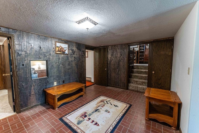 1479 Old Mill Rd, Franklin Grove, IL 61031 - sitting room with brick patterned flooring, wood walls, stairs, and a textured ceiling