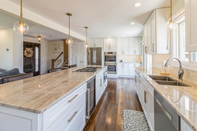 kitchen with a sink, appliances with stainless steel finishes, decorative backsplash, white cabinetry, and light stone counters