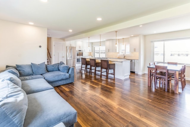 living area featuring dark wood-type flooring, recessed lighting, stairway, and baseboards