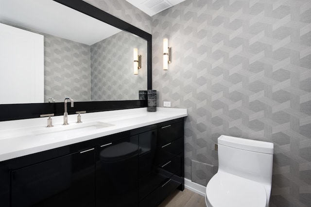 bathroom featuring wood finished floors, toilet, vanity, and baseboards