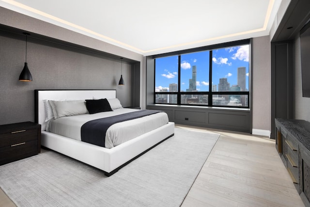 bedroom featuring light wood-style floors, a skyline view, and baseboards