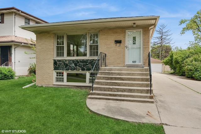 doorway to property featuring brick siding, a lawn, and a garage