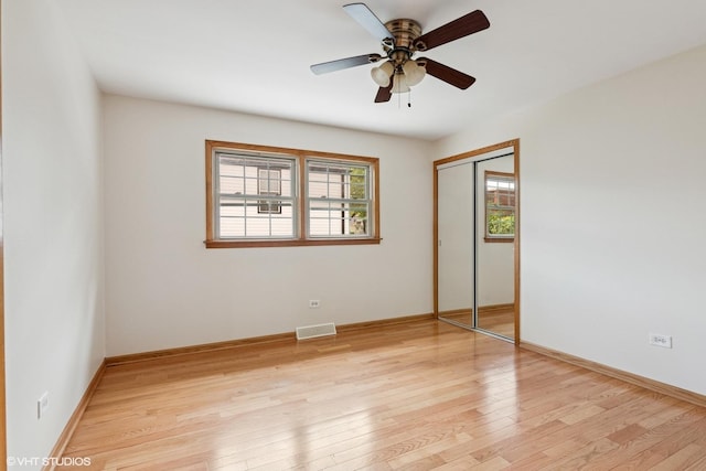 unfurnished bedroom featuring a closet, light wood-type flooring, baseboards, and a ceiling fan