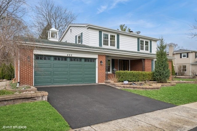 traditional-style house featuring brick siding, an attached garage, driveway, and covered porch