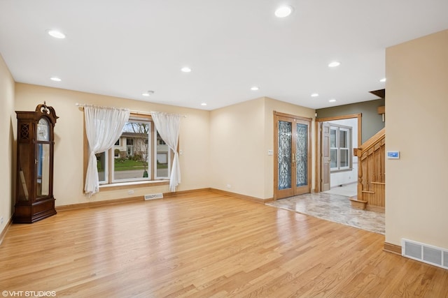 unfurnished living room with light wood-type flooring, baseboards, stairs, and recessed lighting