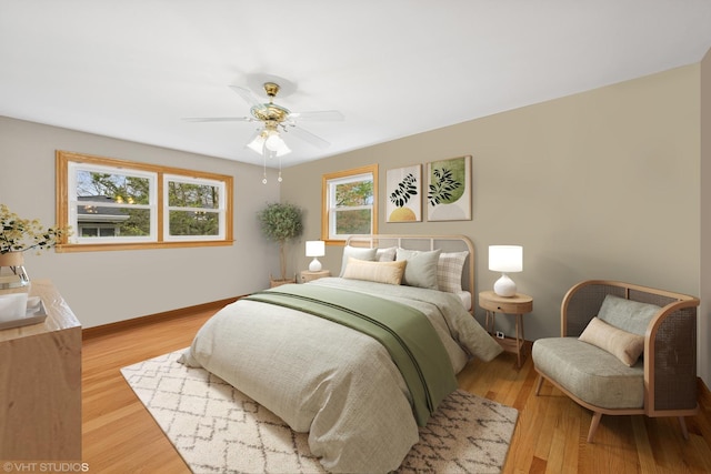bedroom featuring multiple windows, light wood finished floors, baseboards, and a ceiling fan