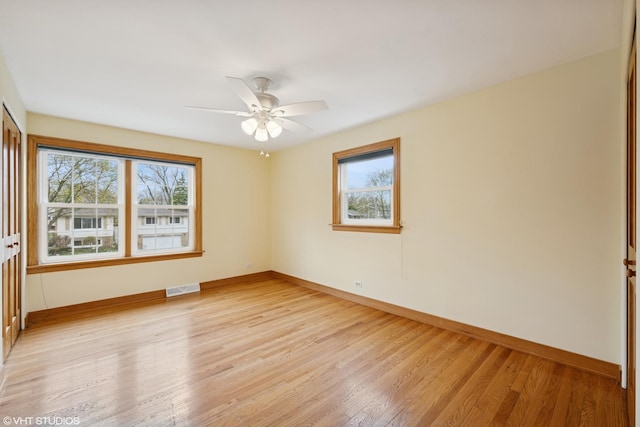 empty room with healthy amount of natural light, baseboards, and light wood finished floors