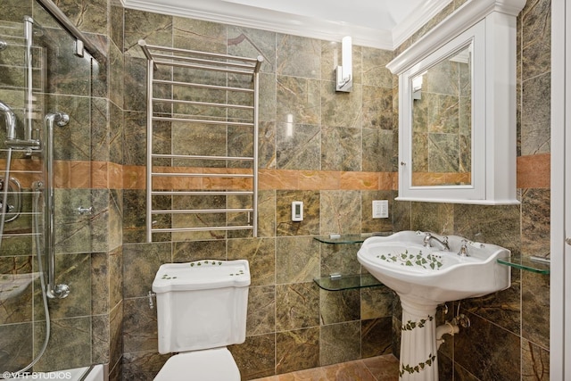 bathroom with a tile shower, toilet, crown molding, and tile walls