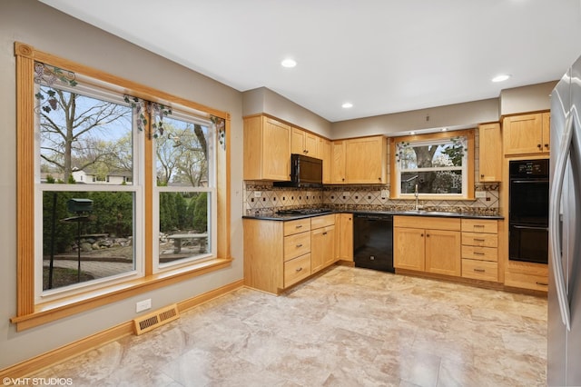 kitchen featuring black appliances, dark countertops, a sink, tasteful backsplash, and light brown cabinets