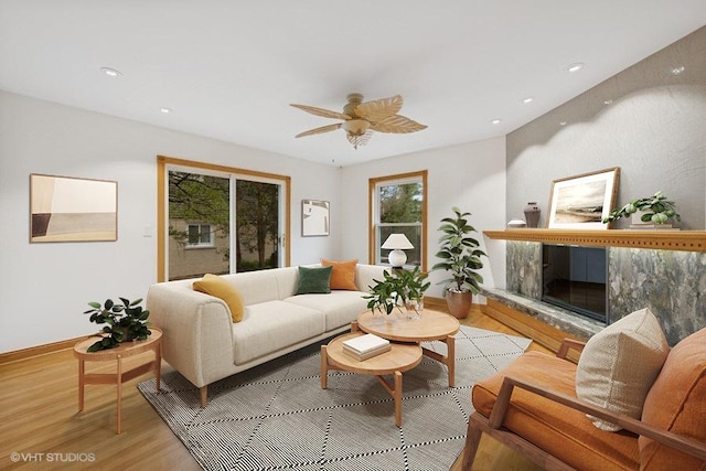 living room with light wood-type flooring, a fireplace, ceiling fan, baseboards, and recessed lighting