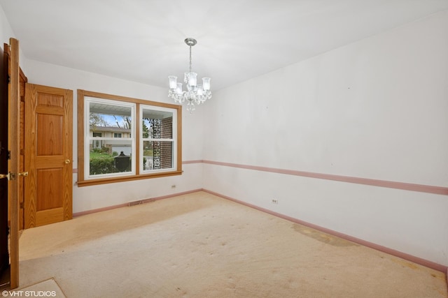 empty room with a chandelier, carpet flooring, and baseboards