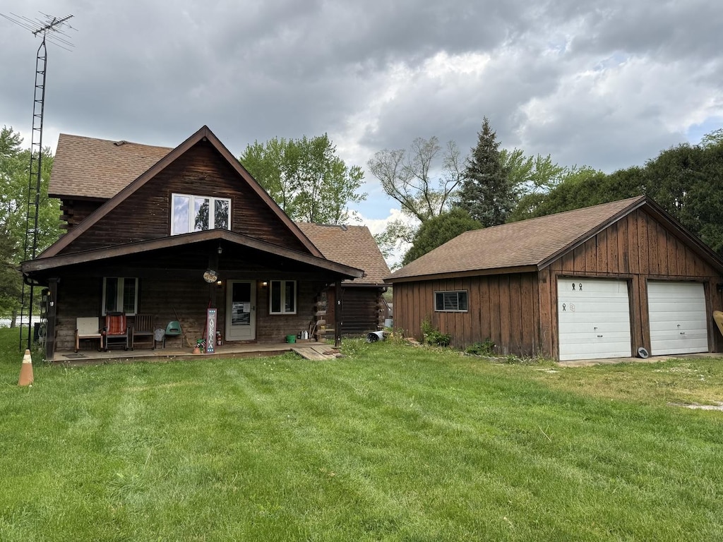 1170 Towpath Ln, Wilmington, IL 60481 - view of front of property featuring a detached garage, a front lawn, covered porch, a shingled roof, and an outbuilding