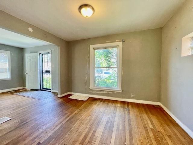 empty room featuring hardwood / wood-style floors, baseboards, and plenty of natural light